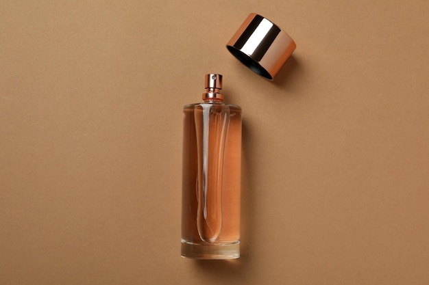 Blank bottle of perfume on light brown background