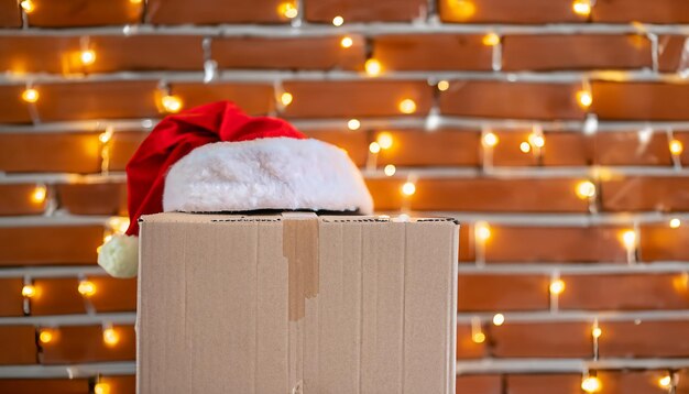 Photo blank brown freight box with santa claus hat on top brick wall with christmas lights