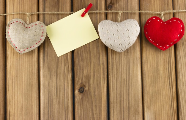 Blank card on a rope with hearts on a wooden