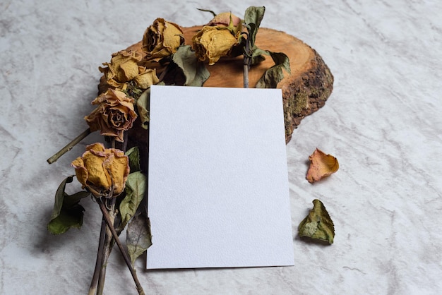 Blank card and wilted flowers on marble background