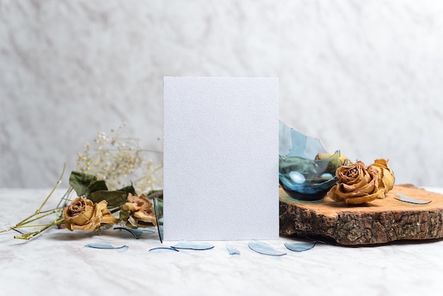 Blank card and wilted flowers on marble background