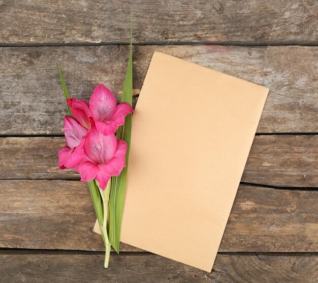 Blank card with beautiful gladiolus on wooden background