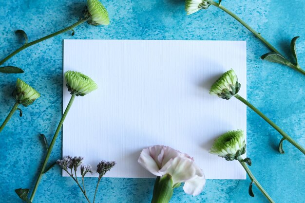 Foto carta bianca con fiori su uno sfondo blu