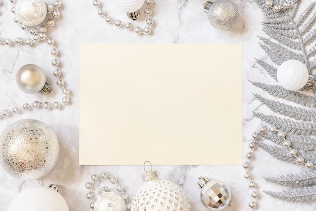 Scheda in bianco con decorazioni di albero di natale in argento e bianco sulla vista del piano d'appoggio in marmo bianco. mockup di biglietto di auguri di natale o capodanno, copia dello spazio. concetto di vacanza invernale