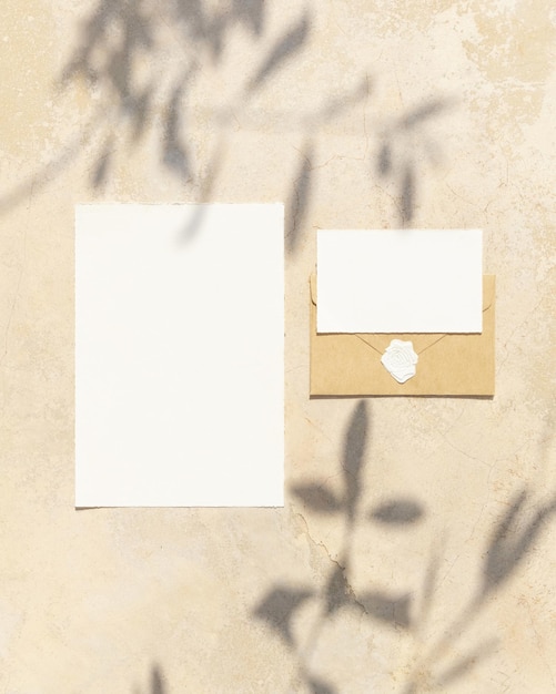 Blank cards on concrete table with olive tree branches and hard shadows wedding mockup