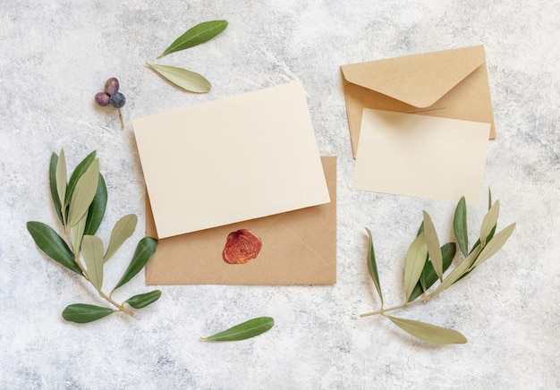 Blank cards and envelopes on table with olive tree\
branches