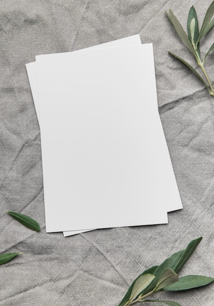 Blank cards with olive branches resting on gray linen fabric
