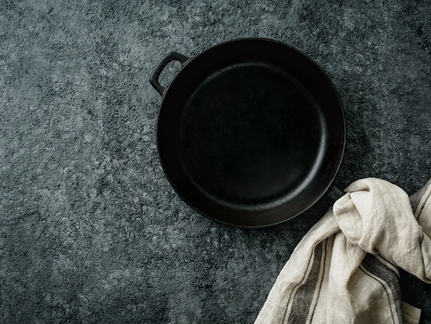 Blank cast iron frying pan on dark grey concrete background