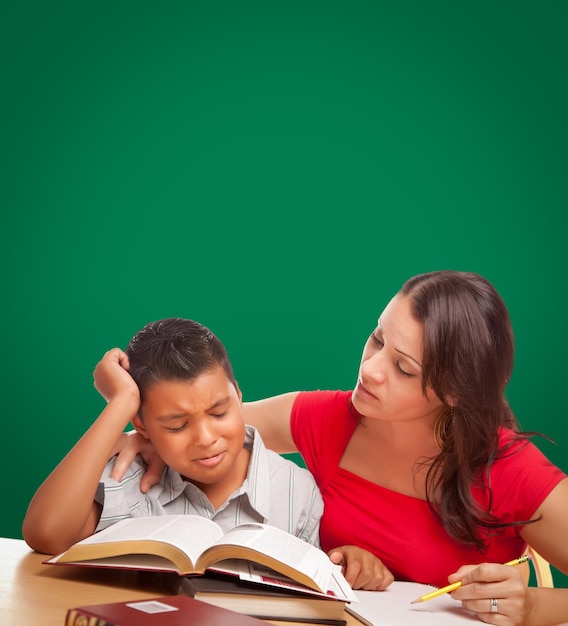 Photo blank chalk board behind hispanic young boy and famale adult studying