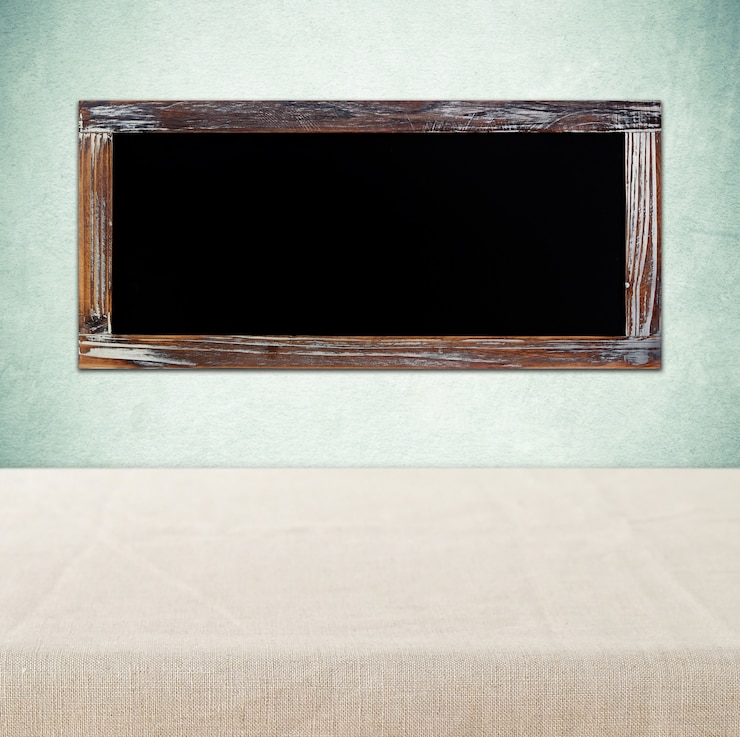 फोटो blank chalkboard hanging on green wall over empty table