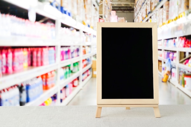 Blank chalkboard standing on sack tablecloth over blur supermarket with bokeh background