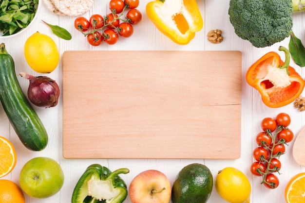 写真 白地にカラフルな野菜や果物に囲まれた空白のまな板