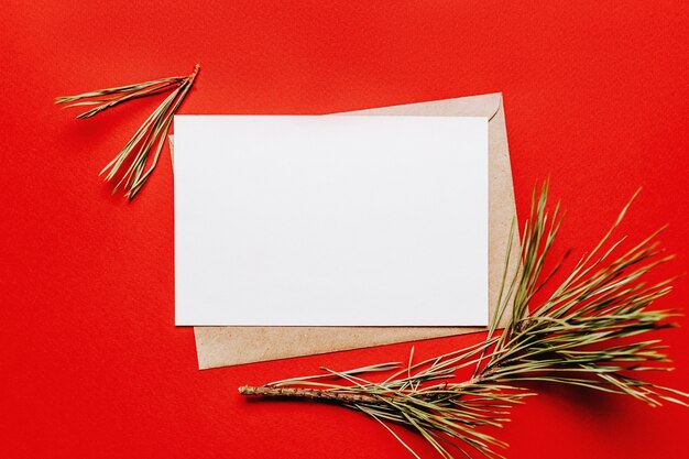 赤い孤立した背景にモミの枝と空白のクリスマスノート。新年のコンセプト