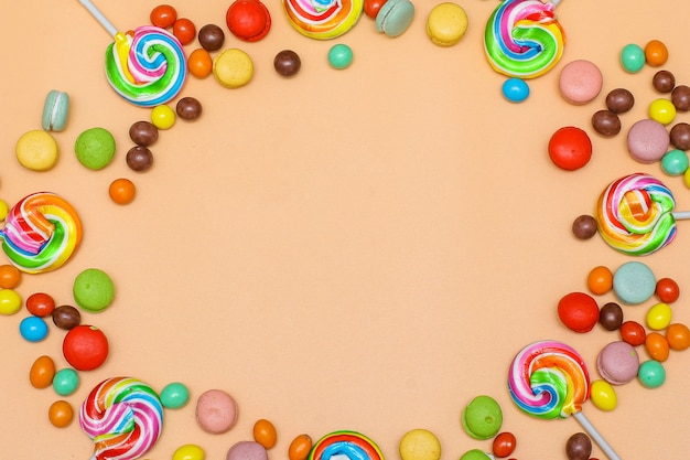 Blank circular frame made with various of colorful candy on cream background Flat lay top view