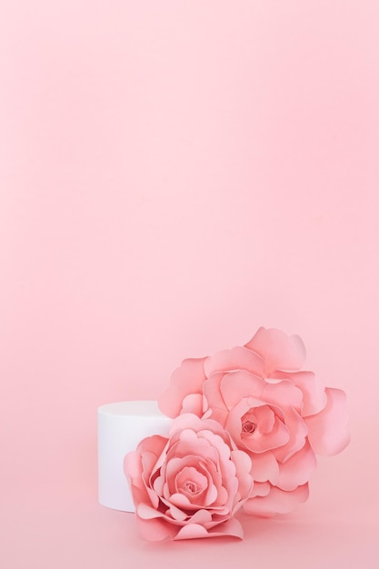 Blank circular platform for product presentation with paper roses on pink background Copy space Vertical photo