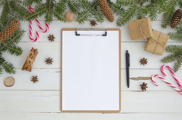 Blank clipboard, Christmas decoration on white wooden background. Flat lay, top view mock-