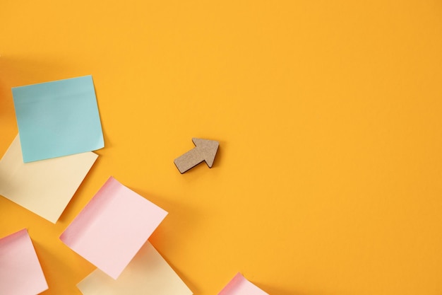 Blank colorful sticky notes and wooden arrows on yellow background flat lay