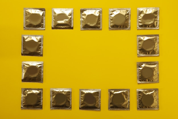 Blank condoms on yellow background, space for text