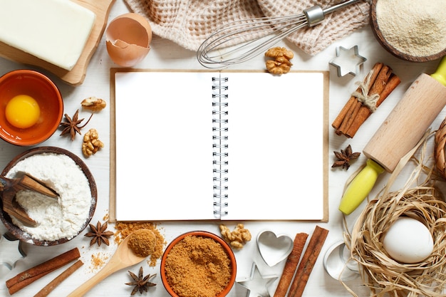 Foto libro di cucina in bianco, ingredienti e utensili per la cottura vista dall'alto