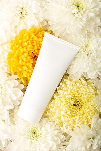 Blank cosmetics tube on the flower petalsFloral backround aroundOrganic production concept