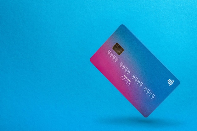 a blank credit card soars in the air with a shadow on a blue background credit card with place to in...