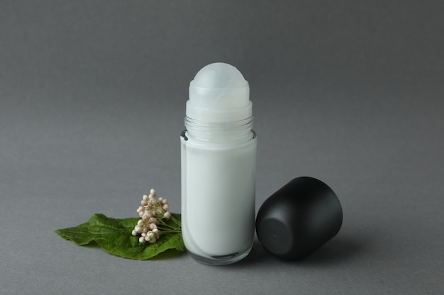 Blank deodorant and flower on gray background