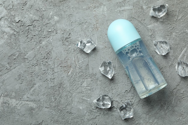 Blank deodorant and ice cubes on gray textured background