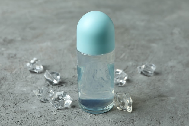 Blank deodorant and ice cubes on gray textured background