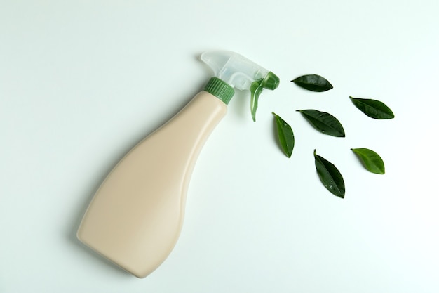 Blank detergent spray bottle and leaves on white isolated background