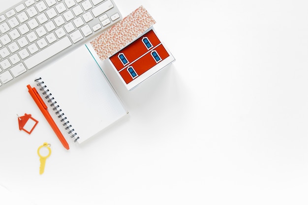 Foto diario in bianco con modello di casa in miniatura e tastiera su sfondo bianco