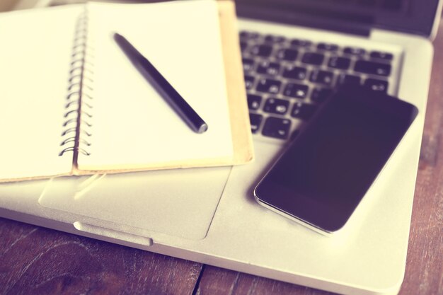 Photo blank diary with pen smartphone and laptop on a wooden table