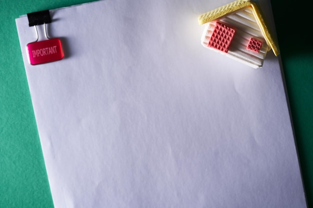 Blank document with paper clip and toy model house