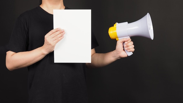 Blank empty white board in man's hand and megaphone on black background