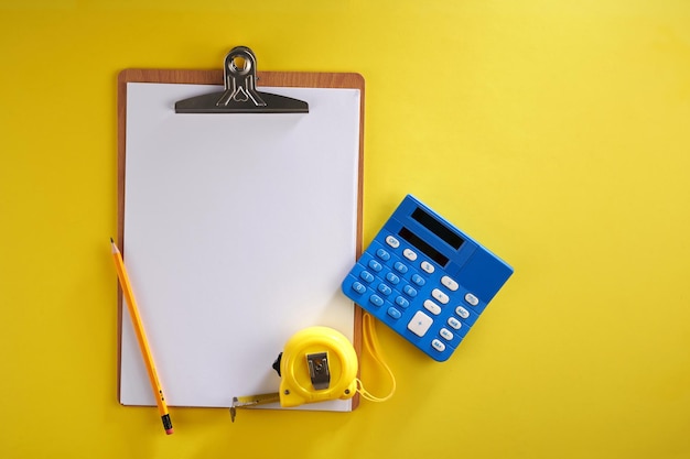 Blank form on clipboard with calculator and tape measure