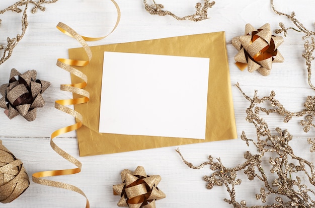 Blank Golden envelope, empty note and golden Christmas toys on wooden rustic, flat lay