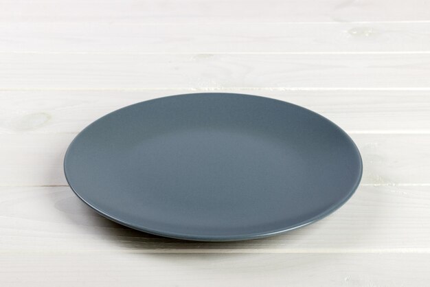 Фото Пустая серая пустая круглая тарелка на деревянном фоне.