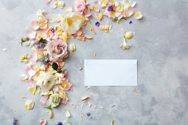 Foto biglietto di auguri vuoto e fiori freschi su uno sfondo di pietra grigia per la progettazione di lavori creativi