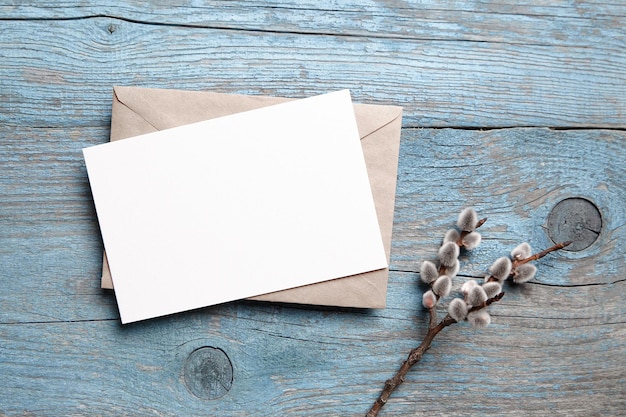 Photo blank greeting card mockup and envelop on blue wood top view flat lay easter holiday fluffy catkins