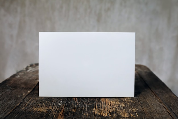 Blank greeting card at wooden vintage table and wall background, letter mock up