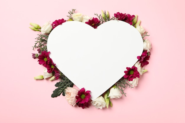 Photo blank heart and different flowers on pink background, space for text