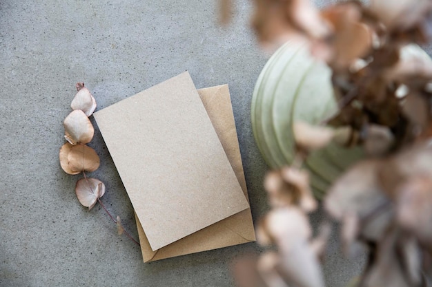 Blank kraft brown invitation stationery card with dried eucalyptus leaves