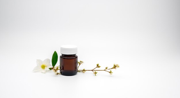 Blank label amber glass bottle and white flowers with branch on white background with copy space, just add your own text