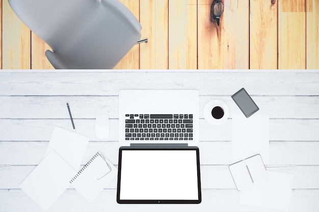 Blank laptop screen with smartphone cup of coffee and blank papers on wooden table mock up