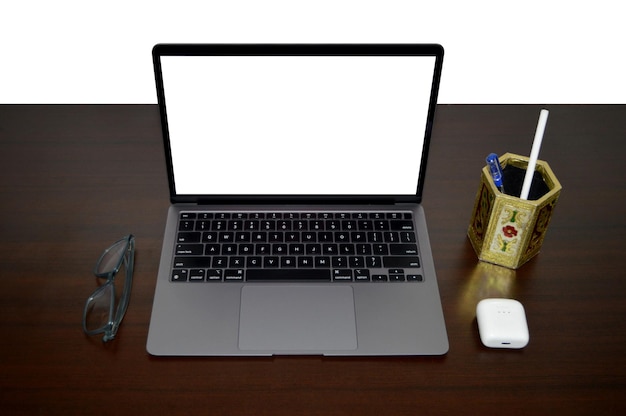 Blank laptop with eyeglasses and earbuds and unique pen stand arrangement