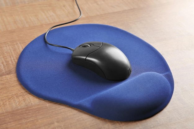 Blank mat and computer mouse on wooden background