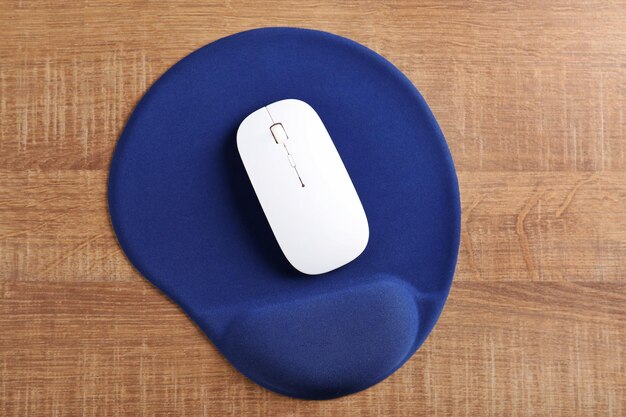 Blank mat and wireless mouse on wooden background