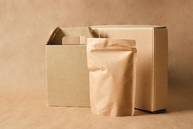 Blank mockup paper bag and two different cardboard boxes leaves\
on brown background eco friendly packaging, paper recycling, zero\
waste, natural products concept. copy space.