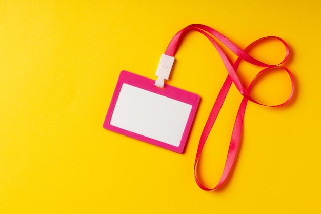 Photo blank nametag on a string on yellow background copy space