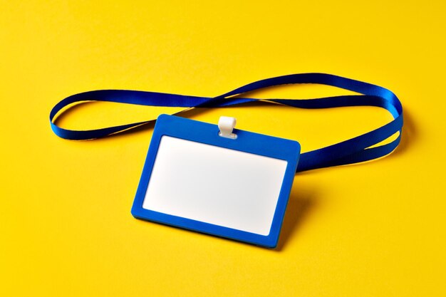 Blank nametag on a string on yellow background copy space