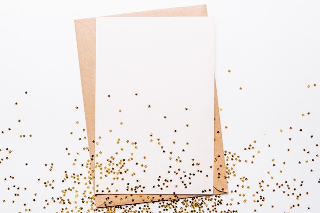 Blank note and gold glitter stars on white background